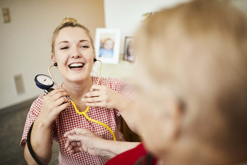 Foto: junge Frau, lächelnd, mit Blutdruckmessgerät